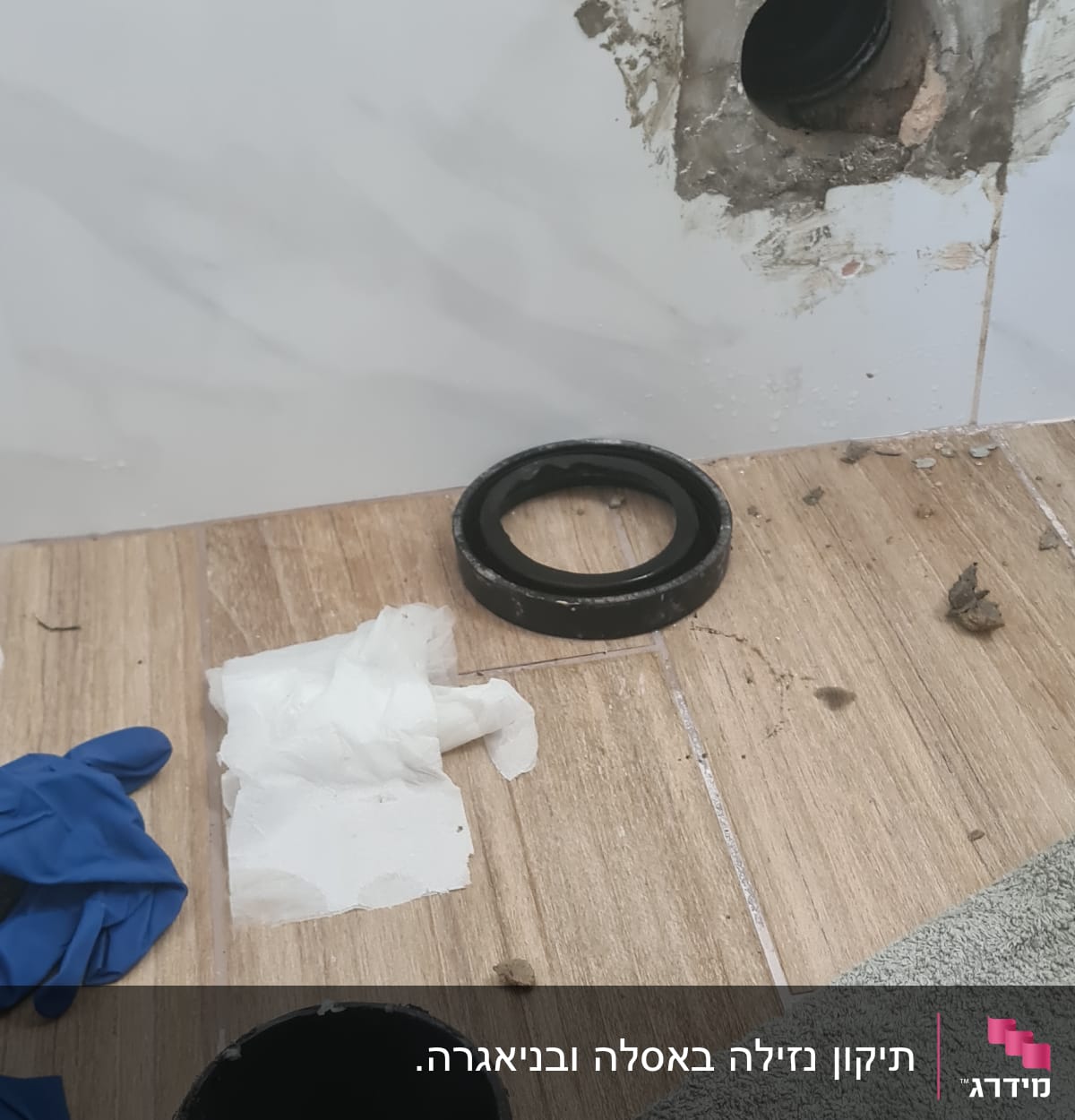 צינור ביוב, כפפות, מגבת וכלי עבודה על הרצפה